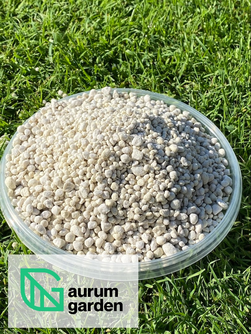 Rudeninių trąšų be azoto granulės baltame indelyje, padėtame ant vešlios, sodriai žalios vejos.